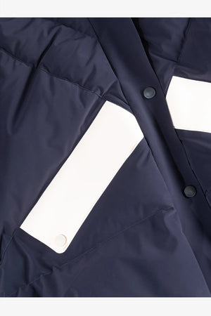Dunkelblaue Jacke mit weißen Einsatzflächen und Druckknöpfen.