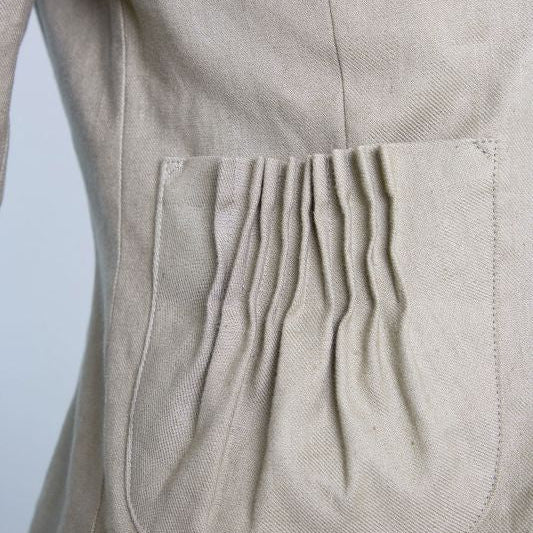 Beige Jacke mit Falten an der Tasche.