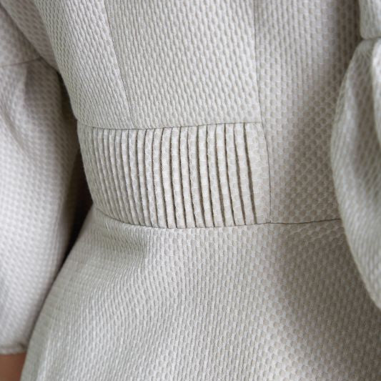 Beige strukturierte Stoffoberfläche mit feinen Falten an der Taille.