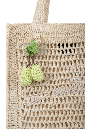 Stylische Handtasche aus geflochtenem Material mit grünen, gehäkelten Anhängern.