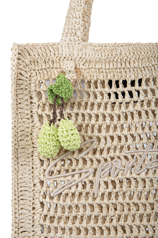 Stylische Handtasche aus geflochtenem Material mit grünen, gehäkelten Anhängern.