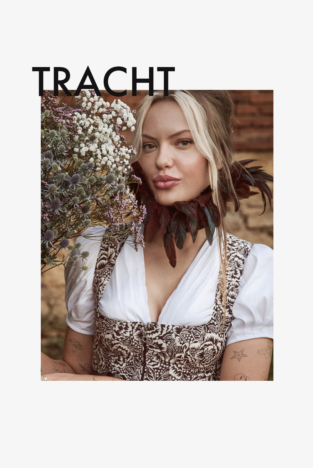 Frau in traditioneller Tracht mit Blumen in der Hand und lässigem Blick.