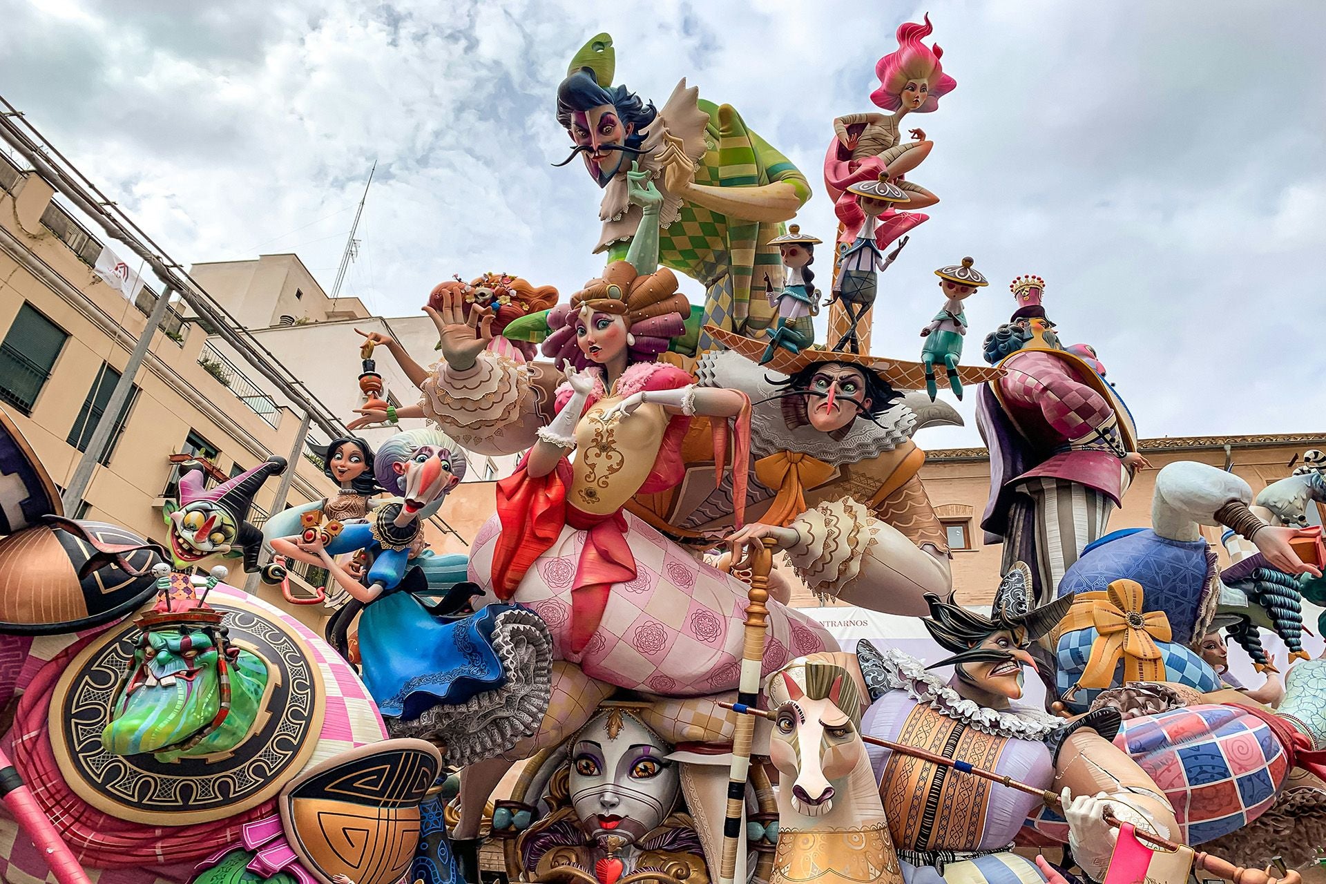Bunte Figuren und Skulpturen aus einer Festveranstaltung befinden sich auf einem Platz unter einem bewölkten Himmel.